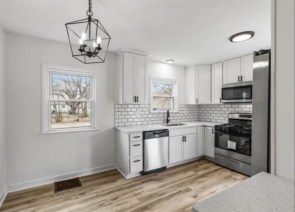 Finished kitchen with white cabinets, subway tile backsplash, and stainless appliances