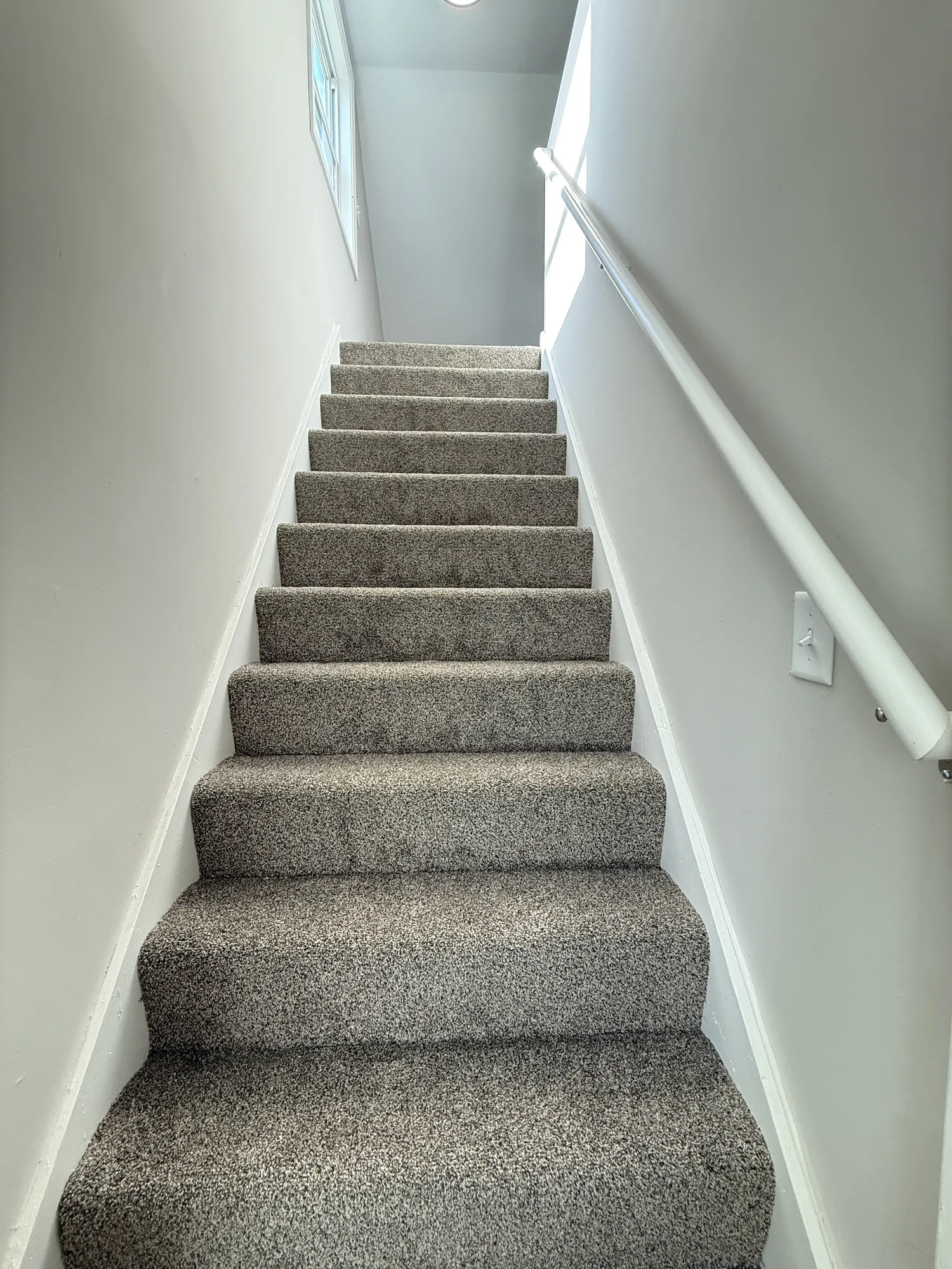 Finished staircase with new carpeted treads, freshly painted walls, and a new white handrail