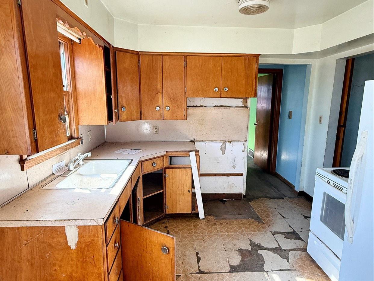 Kitchen before remodel with dated oak cabinets and torn up flooring