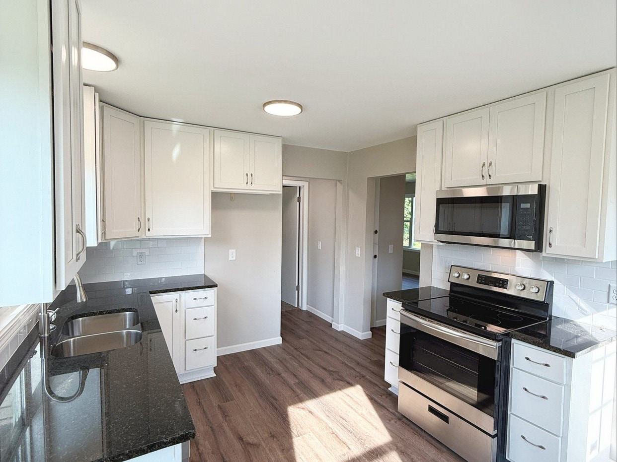 Completed kitchen with white cabinets, granite counters, and stainless appliances