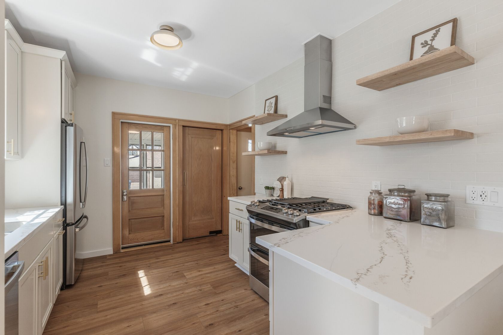 Renovated galley kitchen with quartz counters, vent hood, and open shelving