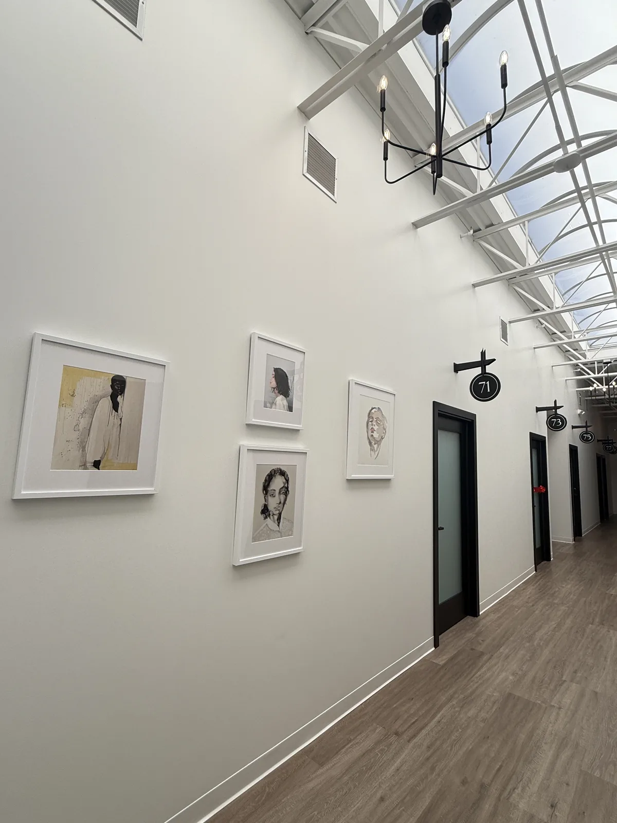 Gallery-hung corridor with framed artwork and pendant lighting