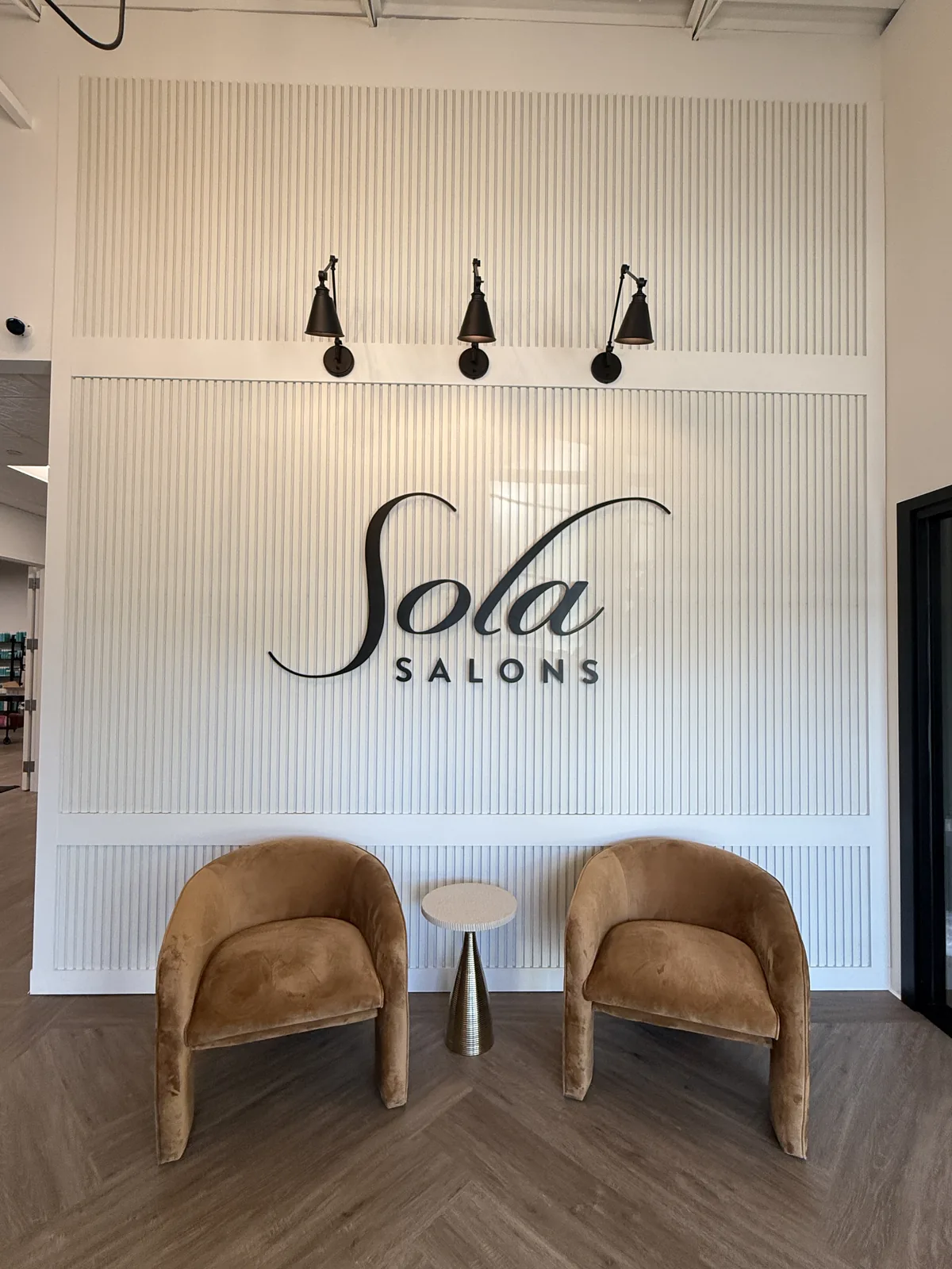 Sola Salon Studios reception with branded feature wall and lounge chairs
